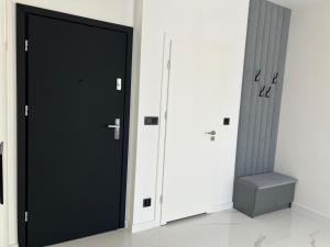 uma porta preta num quarto branco com um banco em Apartmány Ambiente em Kľušov
