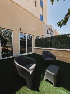 two chairs and a stool in front of a building at Apartamentos La Ruta in Calpe
