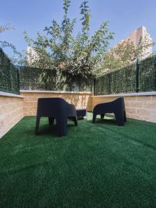 two benches sitting on the grass in a courtyard at Apartamentos La Ruta in Calpe