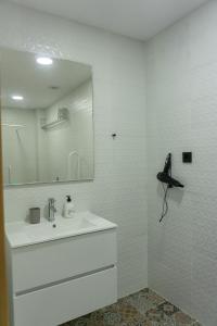 a white bathroom with a sink and a mirror at Apartamentos La Ruta in Calpe