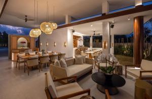 een woonkamer met tafels en stoelen en een eetkamer bij Sumitra Luxury Villas A Pramana Experience in Sanur