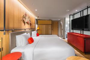 a bedroom with a large white bed and a flat screen tv at Hotel Indigo Alishan, an IHG Hotel in Fanlu
