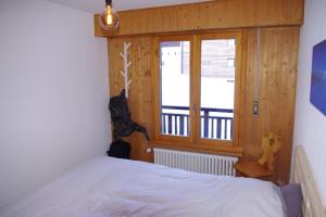 1 dormitorio con cama blanca y ventana en à 2 pas du télécabine en Zinal
