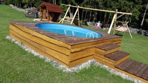 a swimming pool with a wooden deck and a playground at Männiste Holiday Home in Hiievälja