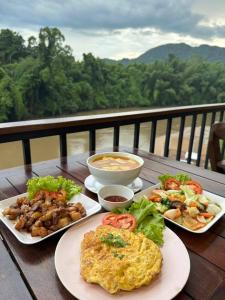 una mesa con tres platos de comida. en เพชรมณีกาญจน์ บีช รีสอร์ท, en Ban Plai Huai Kaeng Riang