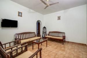a living room with benches and a flat screen tv at Super OYO Pravin Holiday Homes in Calangute