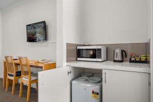 uma cozinha com um micro-ondas e uma mesa em Rowville International Hotel em Rowville