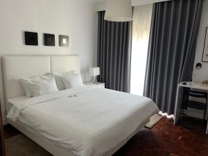 um quarto com uma grande cama branca e uma janela em HOTEL BOUTIQUE a ESPLANADA em Castelo Branco