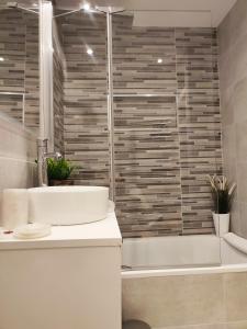 een badkamer met een bad, een wastafel en een douche bij AC Apartaments Suite in Pas de la Casa