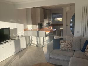a living room with a couch and a tv and a kitchen at The Annexe in Eaglesham