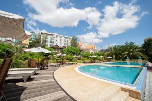 a pool at a resort with benches and umbrellas at Les Jardins Du Bassac in Phnom Penh