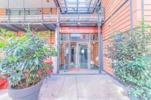 une entrée à un bâtiment avec deux grandes plantes en pot dans l'établissement Residence Montempo Lyon Cite Internationale, à Lyon