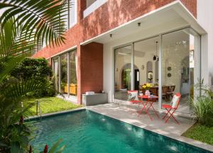 una piscina frente a una casa con mesa y sillas en La Soria Estate en Assagao