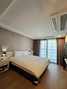 a bedroom with a large bed and a large window at Hotel Air City Jeju in Jeju