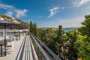 uma varanda com mesas e um guarda-chuva e a água em Genesis Hotel em Loutraki