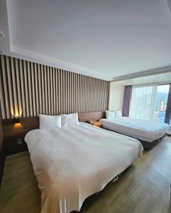 済州市にあるHotel Air City Jejuのベッド2台と窓が備わるホテルルームです。