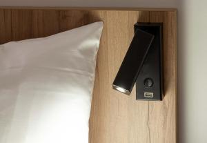 a bed with a speaker next to a white pillow at B&B HOTEL Massieux Genay in Genay