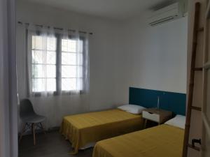 Habitación con 2 camas, ventana y silla en Le Glacis, en Collioure