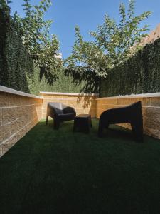 two chairs sitting on the grass next to a wall at Apartamentos La Ruta in Calpe