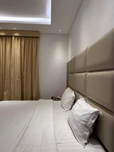 een slaapkamer met een groot bed met 2 kussens bij الأمــــان للشـقـق المـخـدومـة in Al Madinah