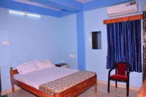 um quarto com uma cama e uma cadeira vermelha em SEA SUN PARADISE em Port Blair