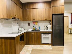 a kitchen with wooden cabinets and a black refrigerator at BRAVO HOME Vinhomes Ocean Park in Hanoi