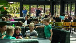 uma multidão de pessoas sentadas em mesas em um restaurante em Camping Wedderbergen em Wedde