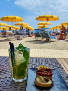 a drink and a sandwich on a table at the beach at Hotel Holiday in Martinsicuro