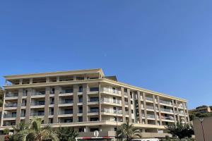 a large building with palm trees in front of it at Splendide T3 neuf au bord de la plage in Propriano