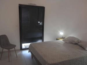 a bedroom with a bed and a chair and a window at Splendide T3 neuf au bord de la plage in Propriano