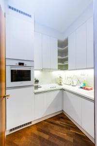 a white kitchen with white appliances and wooden floors at Bellevue Apartment in Prague