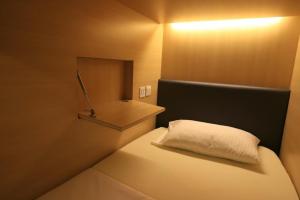 a small bedroom with a bed with a white pillow at Sogor Female Dormitory in George Town
