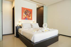 a bedroom with a bed with white sheets and flowers on it at Sunset Mansion Seminyak in Seminyak