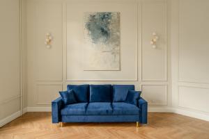 un sofá azul en una sala de estar con una pintura en RentPlanet - Apartament Jana Pawła II, en Wroclaw