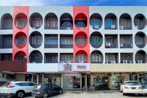 un grand bâtiment avec des fenêtres rouges et des voitures garées dans un parking dans l'établissement Sogor Female Dormitory, à George Town