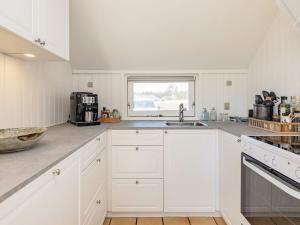 a kitchen with white cabinets and a sink and a window at 8 person holiday home in Vejers Strand in Vejers Strand