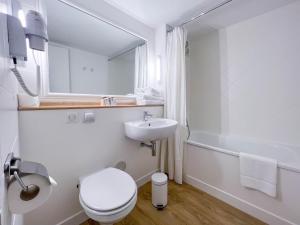 a white bathroom with a toilet and a sink at Kyriad Cannes - Mandelieu in Cannes