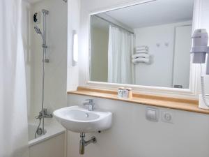a white bathroom with a sink and a mirror at Kyriad Cannes - Mandelieu in Cannes