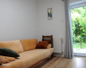 a couch sitting in a living room with a window at Quiet, green, relaxing place- 3 bedroom villa in Balatonfüred