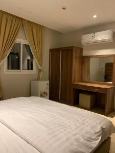 een slaapkamer met een groot wit bed en een dressoir bij الأمــــان للشـقـق المـخـدومـة in Al Madinah