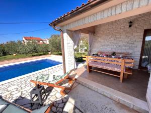 eine Terrasse mit einer Bank neben einem Pool in der Unterkunft Villa Mirela with a comfortable garden and pool in Grandići