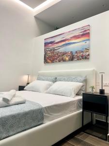 a white bedroom with two beds and a painting on the wall at Chiaia Exclusive Apartment in Naples