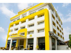 贾姆穆Bloom Hotel - Jammu的黄色和白色的建筑,上面有标志