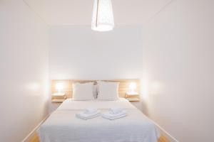 a bedroom with a white bed with two towels on it at Lisbon Sunny Terrace Lapa Santos in Lisbon