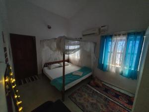 a small bedroom with a bed and two windows at TantraLoka Retreat Centre in Arambol