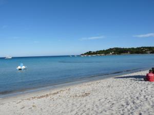 una persona sentada en una playa con un barco en el agua en Monolocale San Teodoro, en San Teodoro