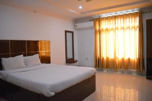 a bedroom with a large bed and a large window at HOTEL SHIVA in Guwahati