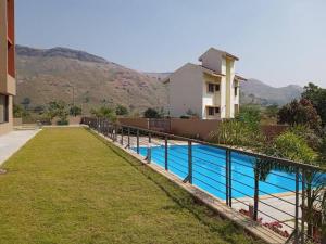 a house with a swimming pool in front of a house at SERENITY - Apartment with Modern Amenities in Igatpuri