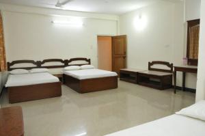 Habitación con 3 camas, escritorio y mesa. en MYSORE MAHALAKSHMI ROOMS en Mysore
