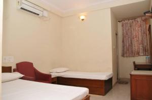 a room with two beds and a chair and a window at MYSORE MAHALAKSHMI ROOMS in Mysore